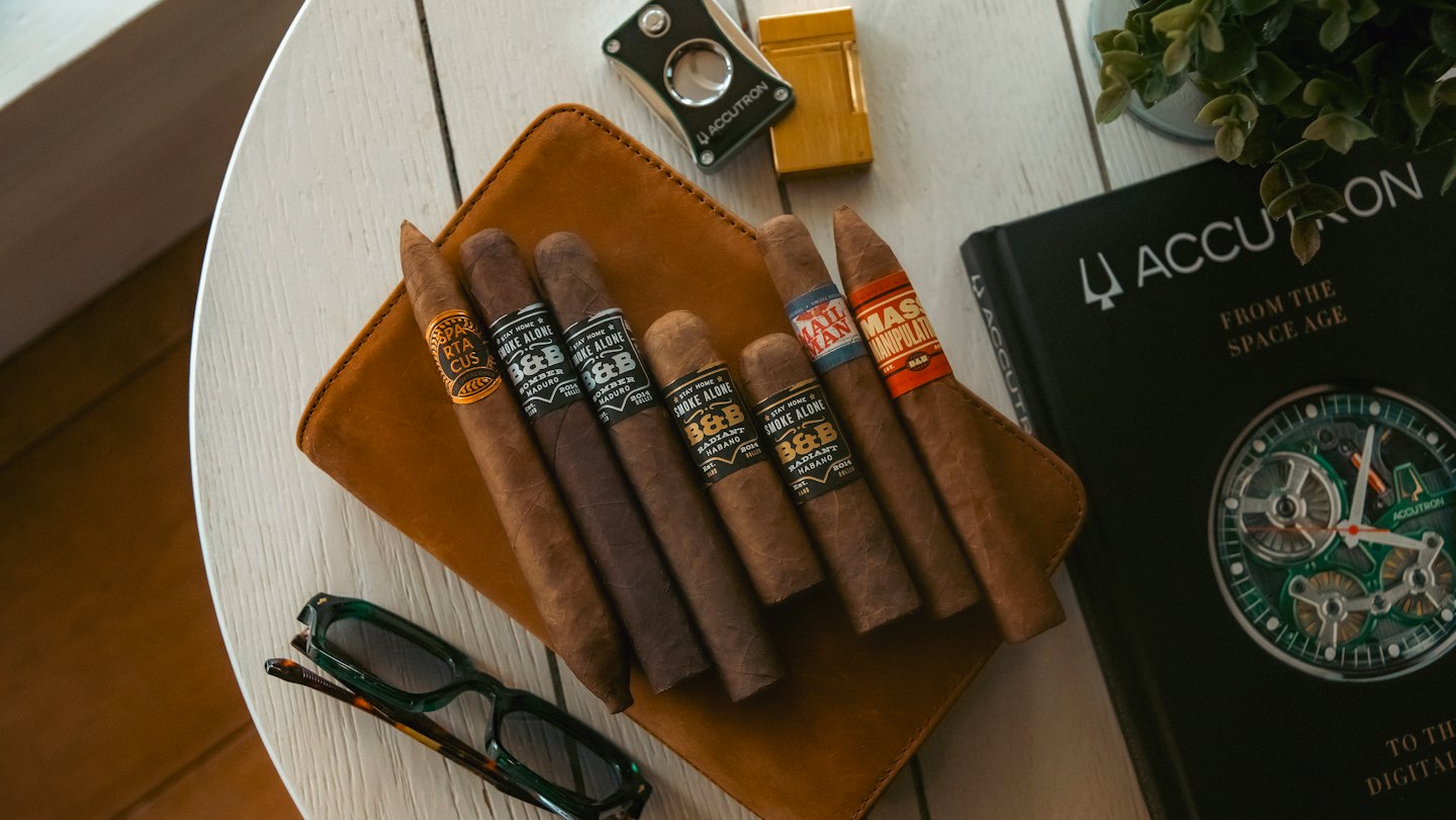 Premium cigars and accessories arranged on a leather case.